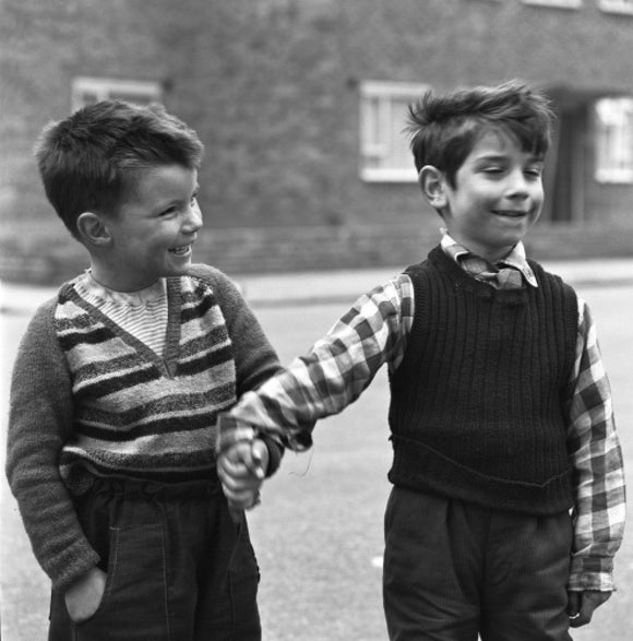 Two boys hold hands in street. c.1955